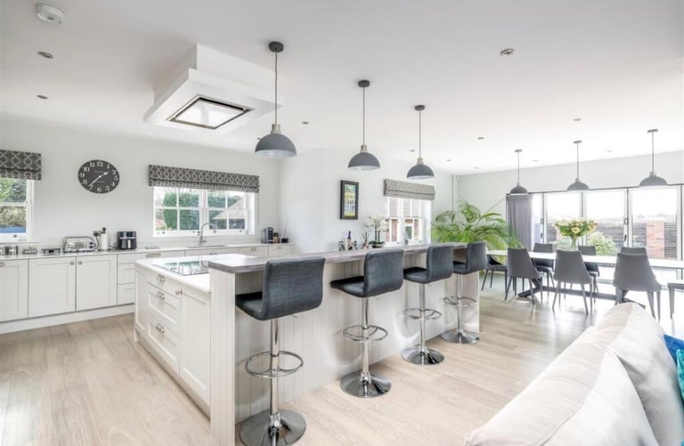 Modern open-concept kitchen and dining area with white cabinetry, island with seating, pendant lights, and hardwood flooring