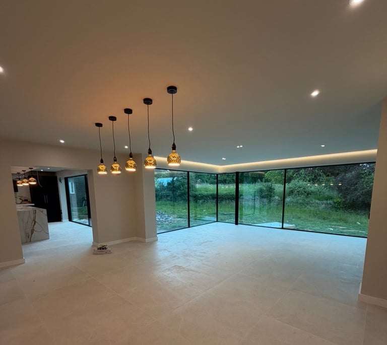 Modern interior with polished concrete floor, golden pendant lights, recessed ceiling lights, and large windows overlooking trees