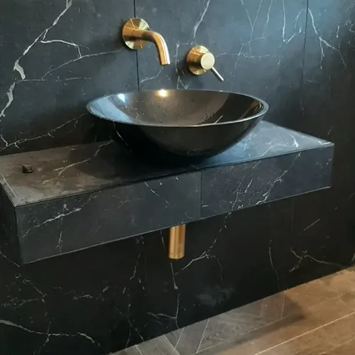 A bathroom sink with a black marble counter top.