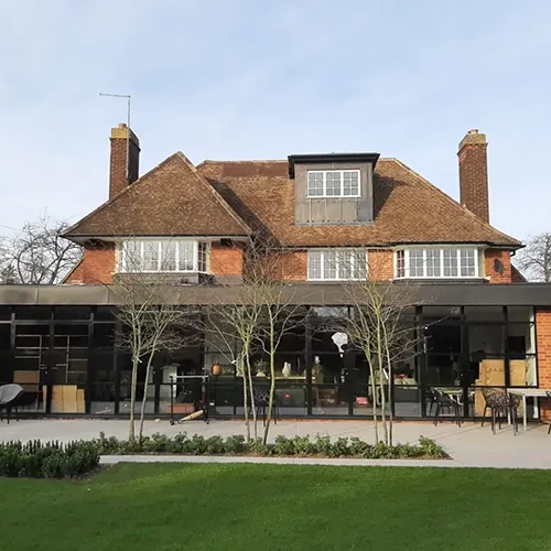 A large brick building with a large lawn in front of it.